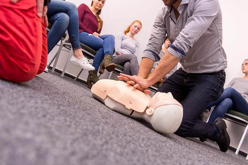 Herzmassage an Erste Hilfe Trainingspuppe bei Ausbildung zum Ersthelfer